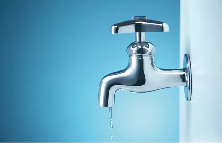 銀色の蛇口から水が一滴ずつ垂れている様子がクローズアップで写されている